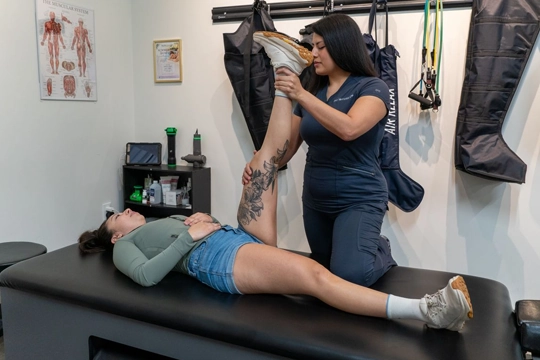 Stretch coach assisting a client with a raised leg stretch on a therapy table