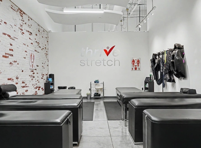 Stretch therapy room with multiple treatment tables, equipment, and the Thrive Stretch logo